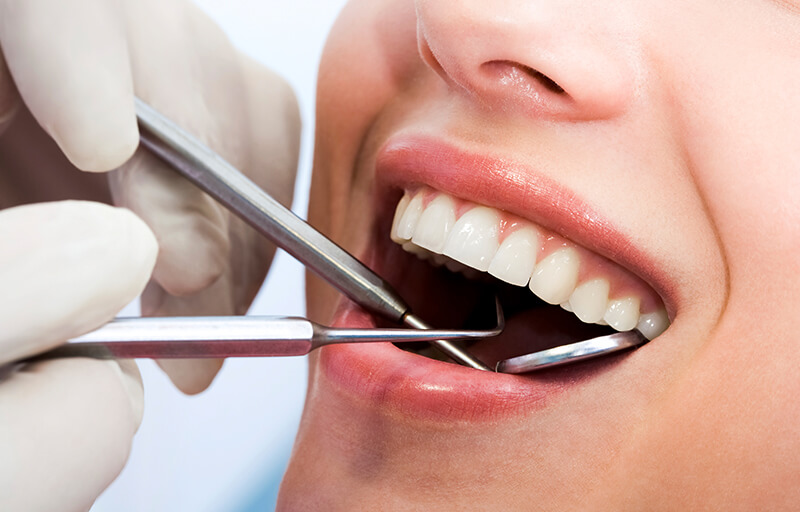 Dentist using dental instruments inside of mouth
