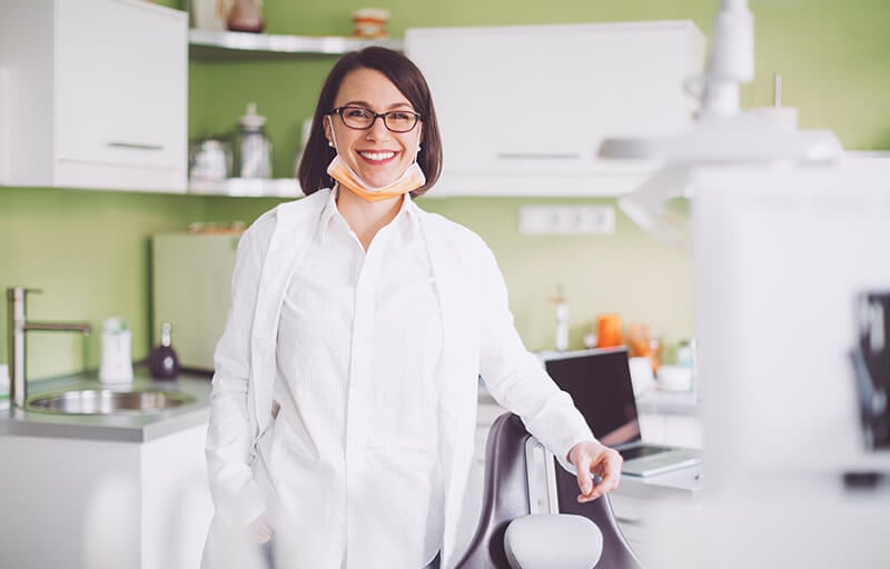 Dentista Geral com paciente e assistente dentário.