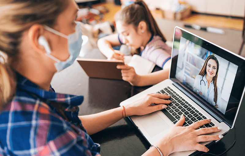 Woman video chatting with doctor on laptop