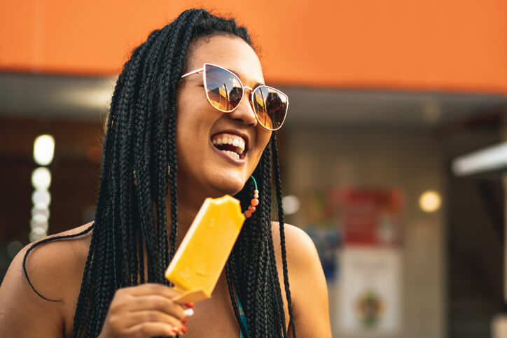 young lady wearing sunglasses eating a popsicle